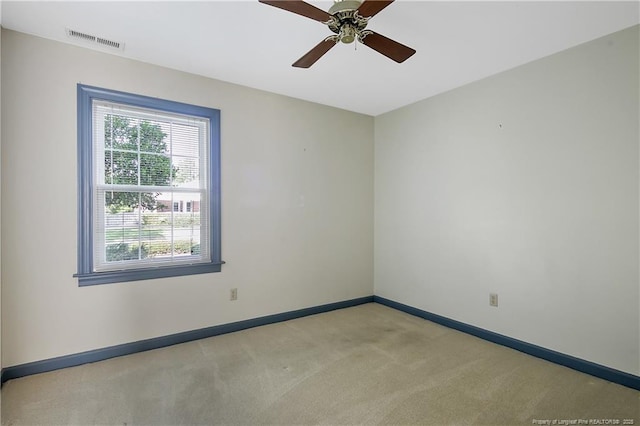 empty room featuring visible vents, baseboards, a ceiling fan, and light carpet