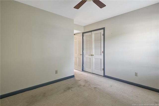 unfurnished bedroom featuring carpet, baseboards, a closet, and a ceiling fan