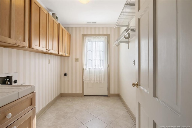 washroom with cabinet space, light tile patterned flooring, visible vents, baseboards, and wallpapered walls