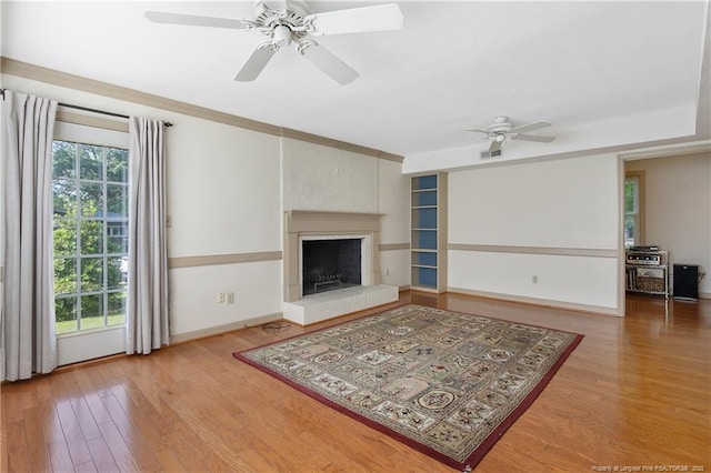 unfurnished living room with baseboards, visible vents, ceiling fan, wood finished floors, and a fireplace