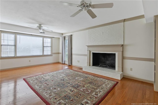 living area with a brick fireplace, wood finished floors, baseboards, and ceiling fan