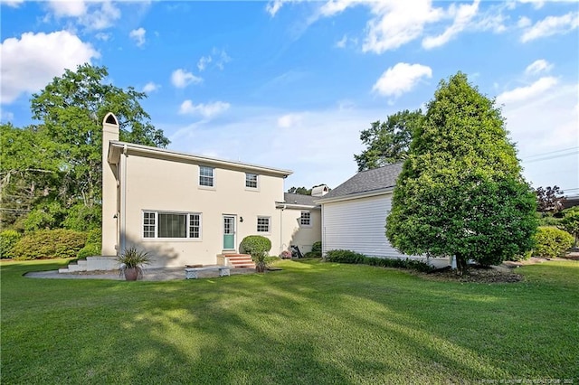 rear view of house featuring a yard, stucco siding, and a chimney