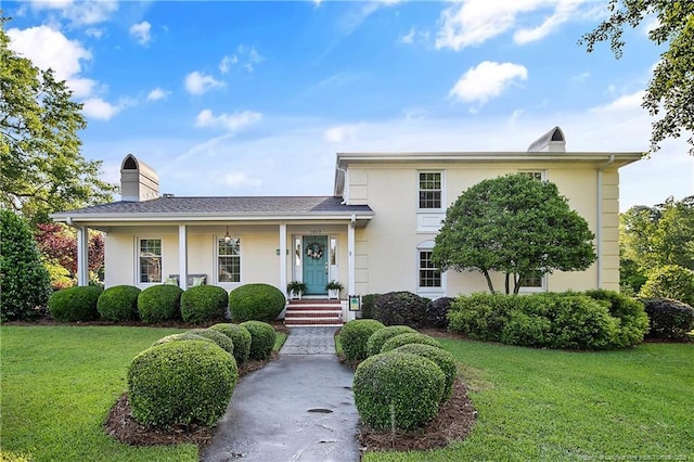 split level home featuring a porch, a chimney, and a front yard