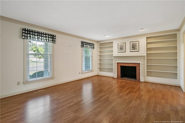 unfurnished living room featuring ornamental molding, plenty of natural light, and wood finished floors