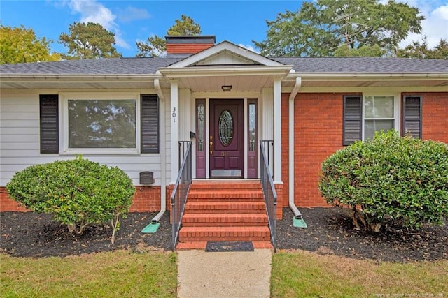 property entrance with a chimney, brick siding, and a shingled roof