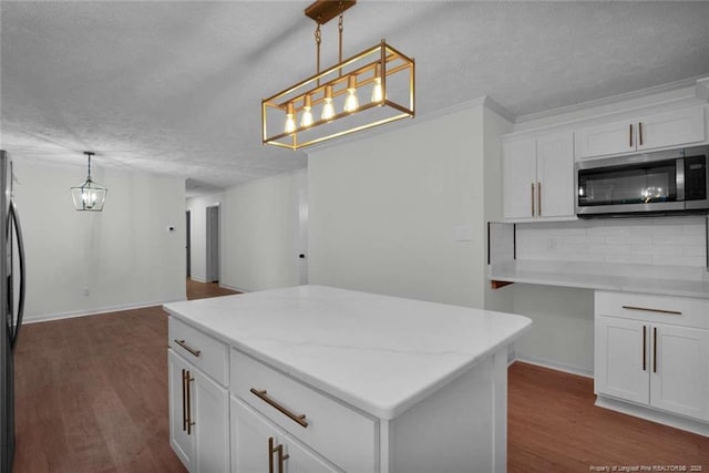 kitchen with an inviting chandelier, a textured ceiling, and stainless steel microwave