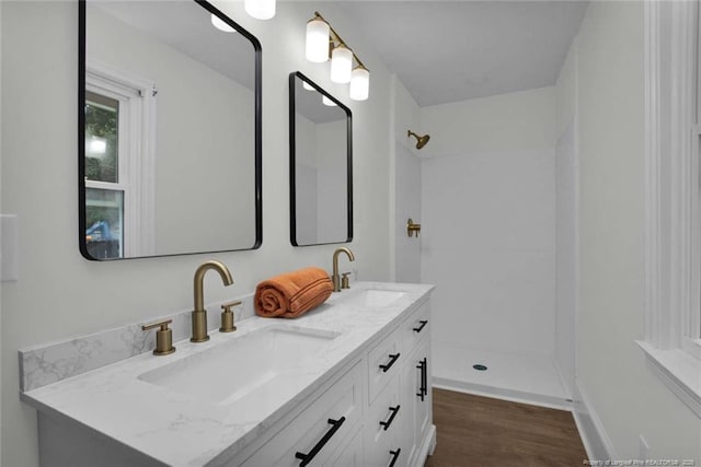 full bath with walk in shower, wood finished floors, and a sink