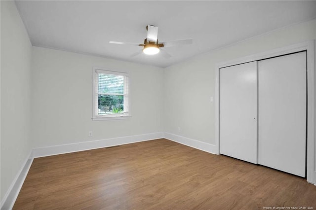 unfurnished bedroom with a closet, wood finished floors, baseboards, and ceiling fan