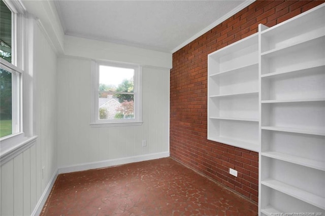spare room with baseboards, brick wall, and crown molding