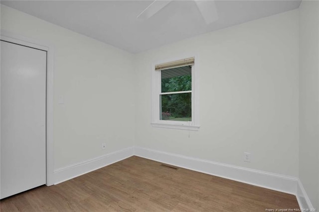 unfurnished room featuring visible vents, wood finished floors, and baseboards