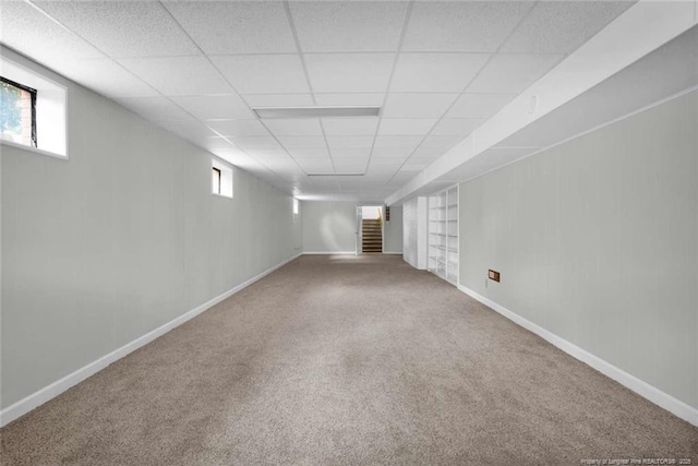 below grade area with carpet, baseboards, and a paneled ceiling