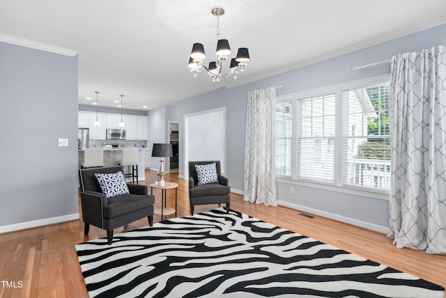 sitting room featuring a chandelier, baseboards, ornamental molding, and light wood finished floors