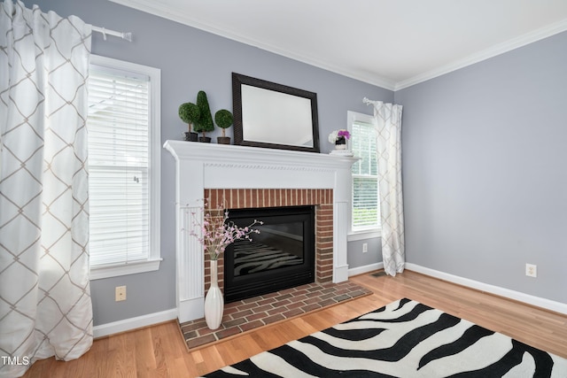 living area featuring wood finished floors, crown molding, baseboards, and a brick fireplace