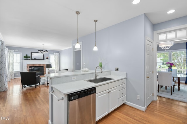 kitchen with a sink, stainless steel dishwasher, a chandelier, light wood finished floors, and light countertops