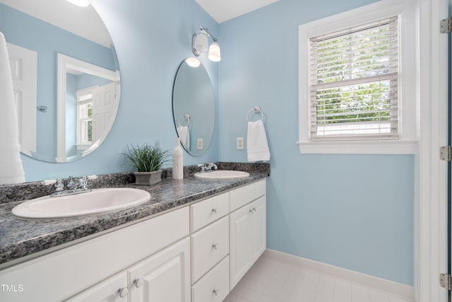 full bathroom featuring double vanity and baseboards