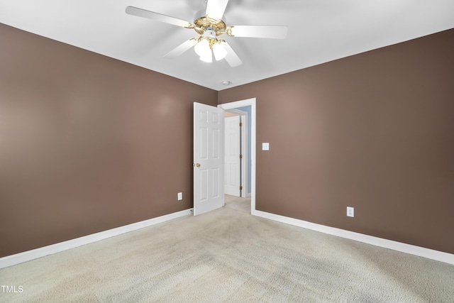 empty room with a ceiling fan, light carpet, and baseboards