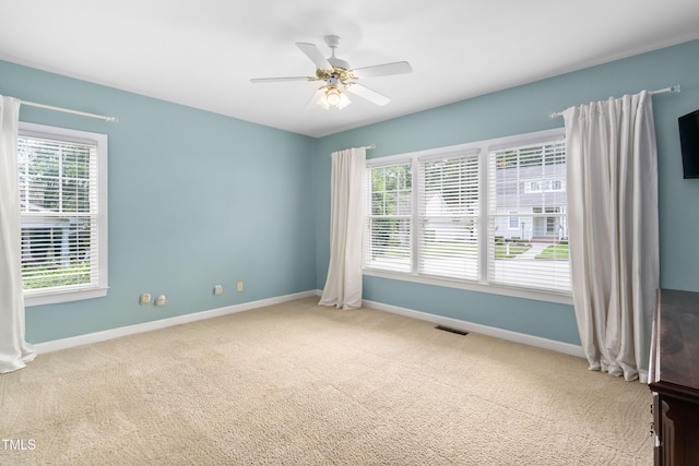 carpeted spare room with baseboards, plenty of natural light, and a ceiling fan