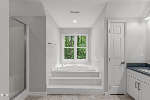 bathroom featuring a garden tub, a stall shower, baseboards, and vanity