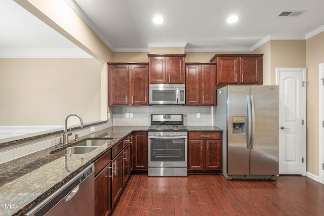 507 Brier Crossings Loop, Durham, NC 27703 - kitchen with appliances with stainless steel finishes, dark stone countertops, dark wood-style flooring, ornamental molding, and tasteful backsplash