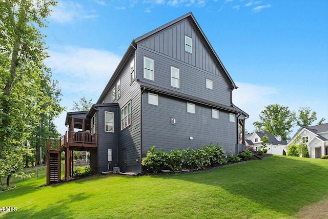 rear view of property featuring board and batten siding, a deck, stairway, and a yard