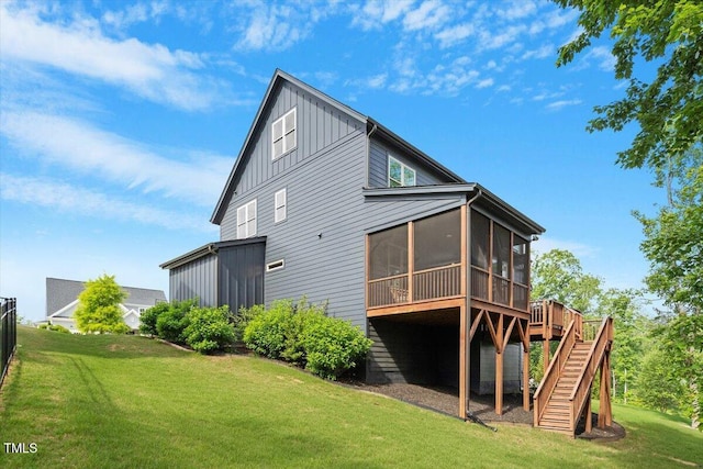 rear view of house with a sunroom, board and batten siding, stairway, a yard, and a deck