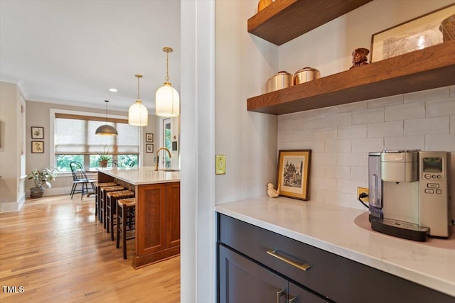 bar featuring light wood-style flooring, pendant lighting, baseboards, a sink, and recessed lighting