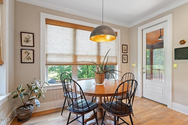 dining area featuring plenty of natural light, light wood-style flooring, crown molding, and baseboards