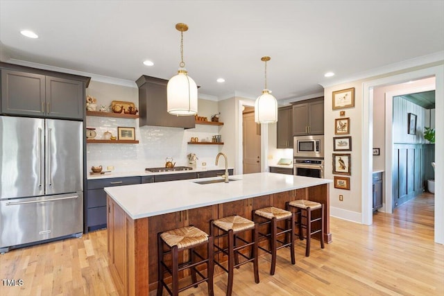kitchen featuring stainless steel appliances, open shelves, a sink, light wood-style floors, and tasteful backsplash
