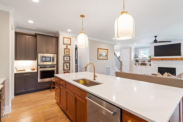 kitchen featuring appliances with stainless steel finishes, a sink, crown molding, light countertops, and ceiling fan
