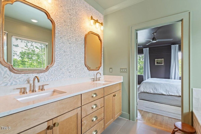 ensuite bathroom with double vanity, ceiling fan, wallpapered walls, and ornamental molding