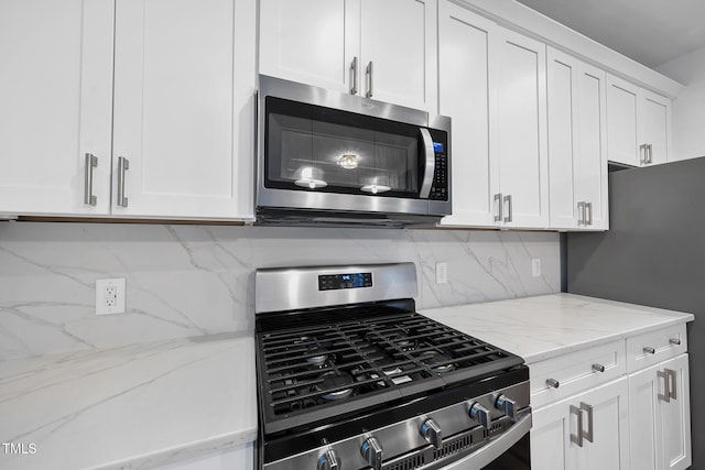 kitchen featuring appliances with stainless steel finishes, white cabinetry, tasteful backsplash, and light stone countertops