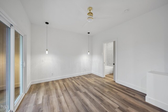 empty room with wood finished floors, baseboards, and a ceiling fan