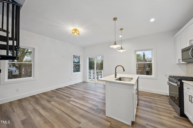 kitchen with stainless steel microwave, range with gas stovetop, a sink, wood finished floors, and recessed lighting
