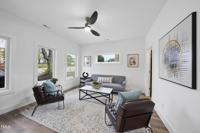 living area featuring healthy amount of natural light, baseboards, and a ceiling fan