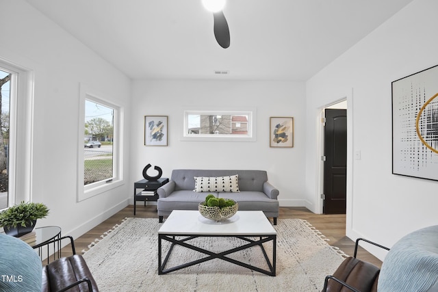 living area featuring wood finished floors, baseboards, and a ceiling fan