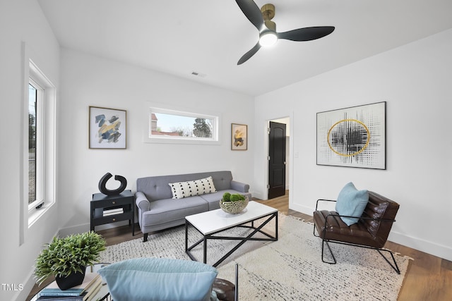 living room featuring baseboards, ceiling fan, and wood finished floors