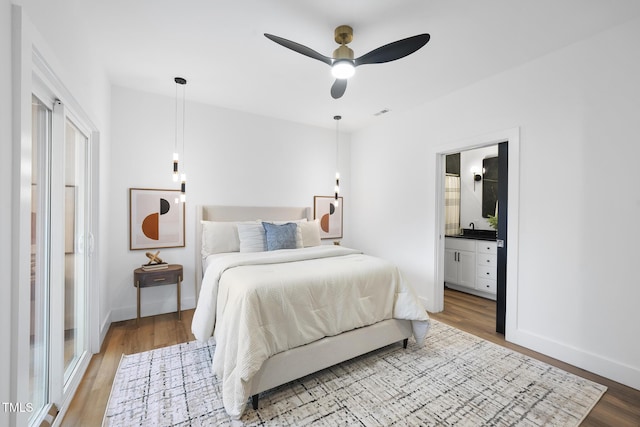 bedroom featuring wood finished floors, ensuite bathroom, and baseboards
