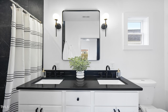 bathroom with double vanity and toilet