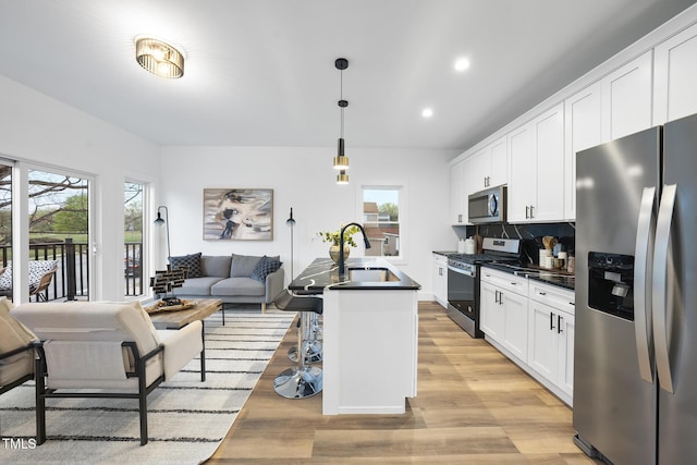 kitchen with appliances with stainless steel finishes, dark countertops, plenty of natural light, recessed lighting, and white cabinets
