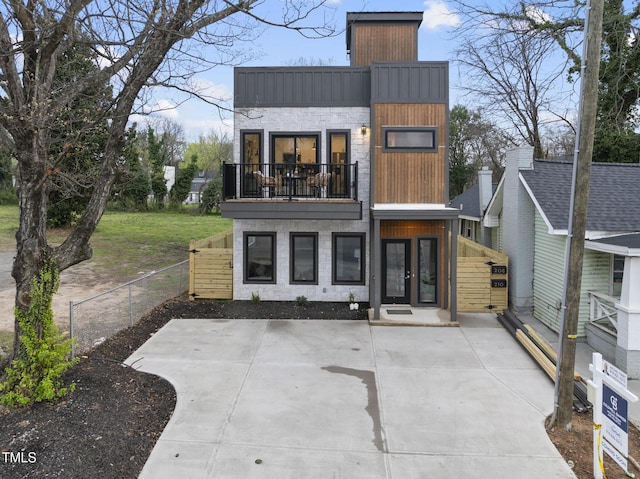 rear view of property featuring a balcony and fence