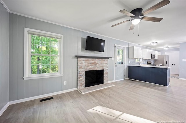 unfurnished living room featuring crown molding, baseboards, a ceiling fan, and visible vents