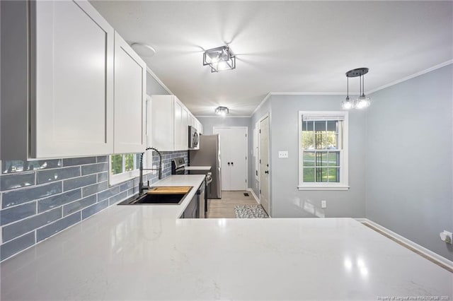 kitchen featuring a sink, crown molding, backsplash, white cabinets, and appliances with stainless steel finishes