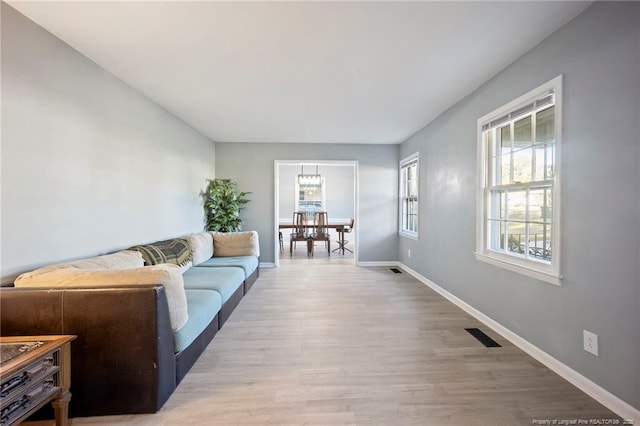 living area featuring baseboards, visible vents, and wood finished floors