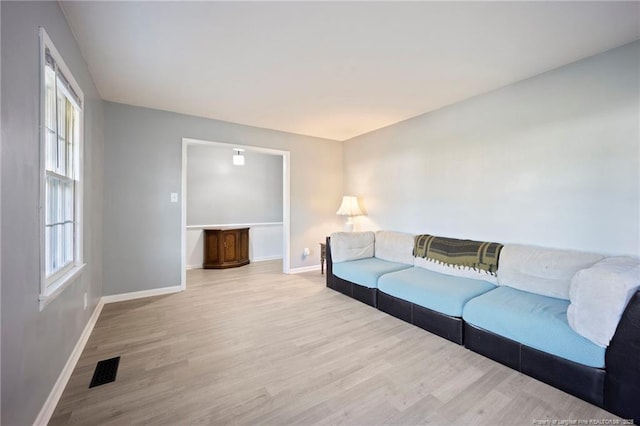 living room with baseboards, visible vents, and light wood-style floors