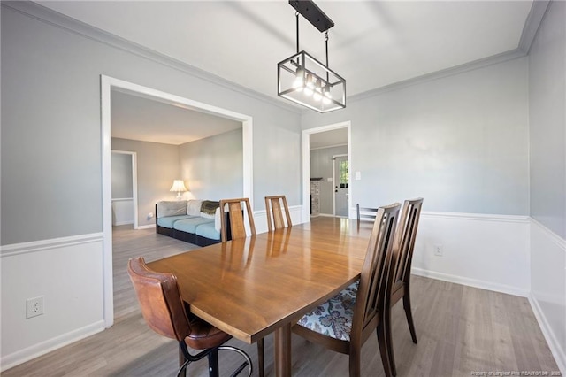 dining area with wood finished floors, baseboards, and ornamental molding
