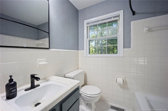 full bathroom featuring a wainscoted wall, tile walls, toilet, and visible vents