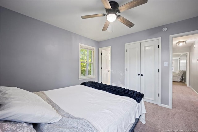 bedroom with light colored carpet, baseboards, a closet, and a ceiling fan