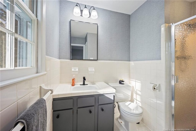 full bath with a stall shower, vanity, tile walls, and toilet