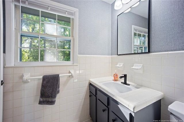 bathroom featuring wainscoting, vanity, toilet, and a healthy amount of sunlight