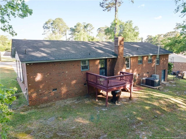 back of house with a chimney, a wooden deck, central air condition unit, a shingled roof, and brick siding